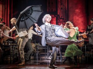 hermes Dressed as Hermes, holding an umbrella, kicking her right leg